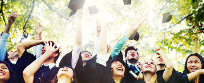 looking up at students throwing graduation hats up into a cirlce of trees