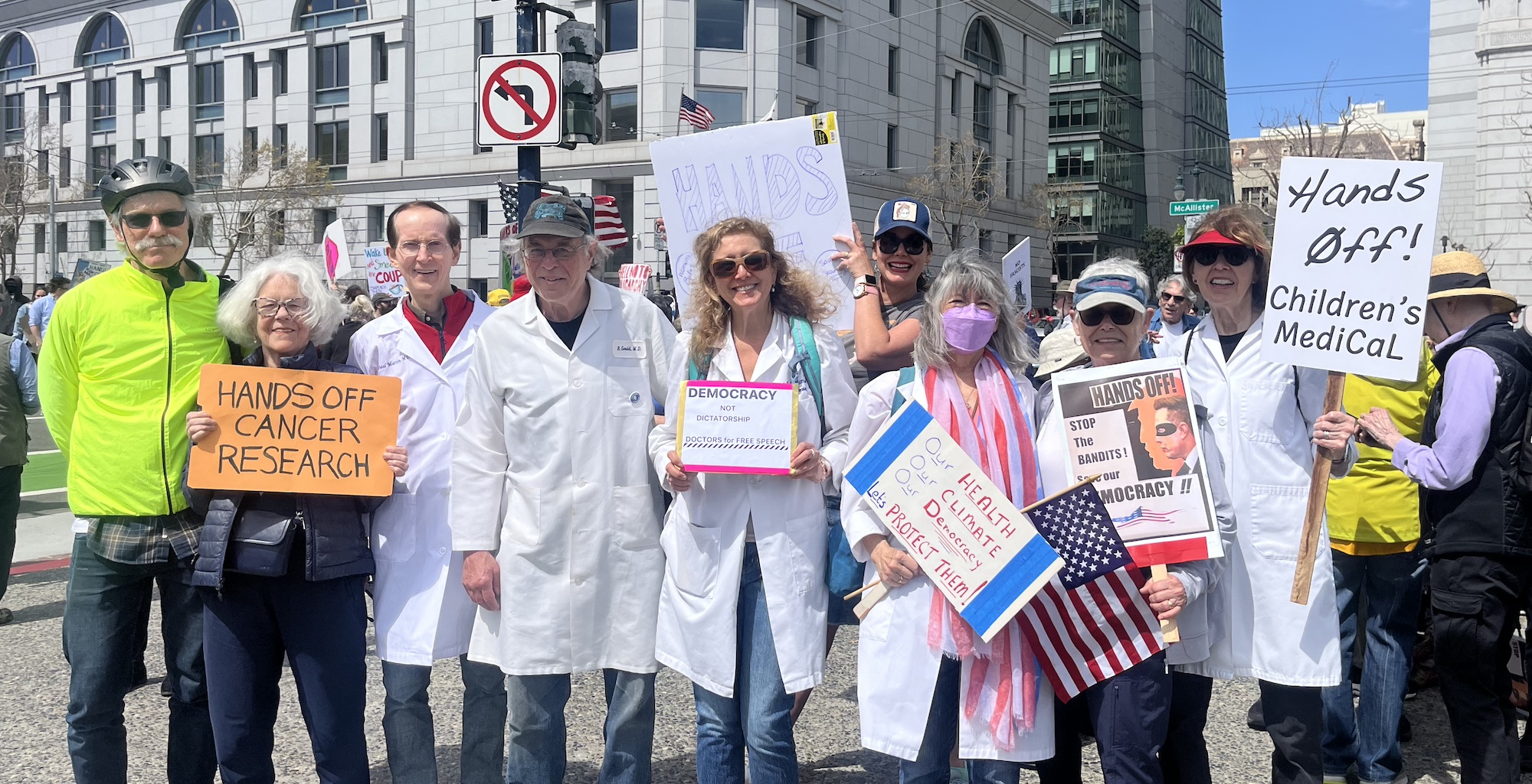 health professionals in their white coats with signs at Hands Off rally