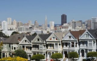 Row of Victorian houses and SF skyline behind them
